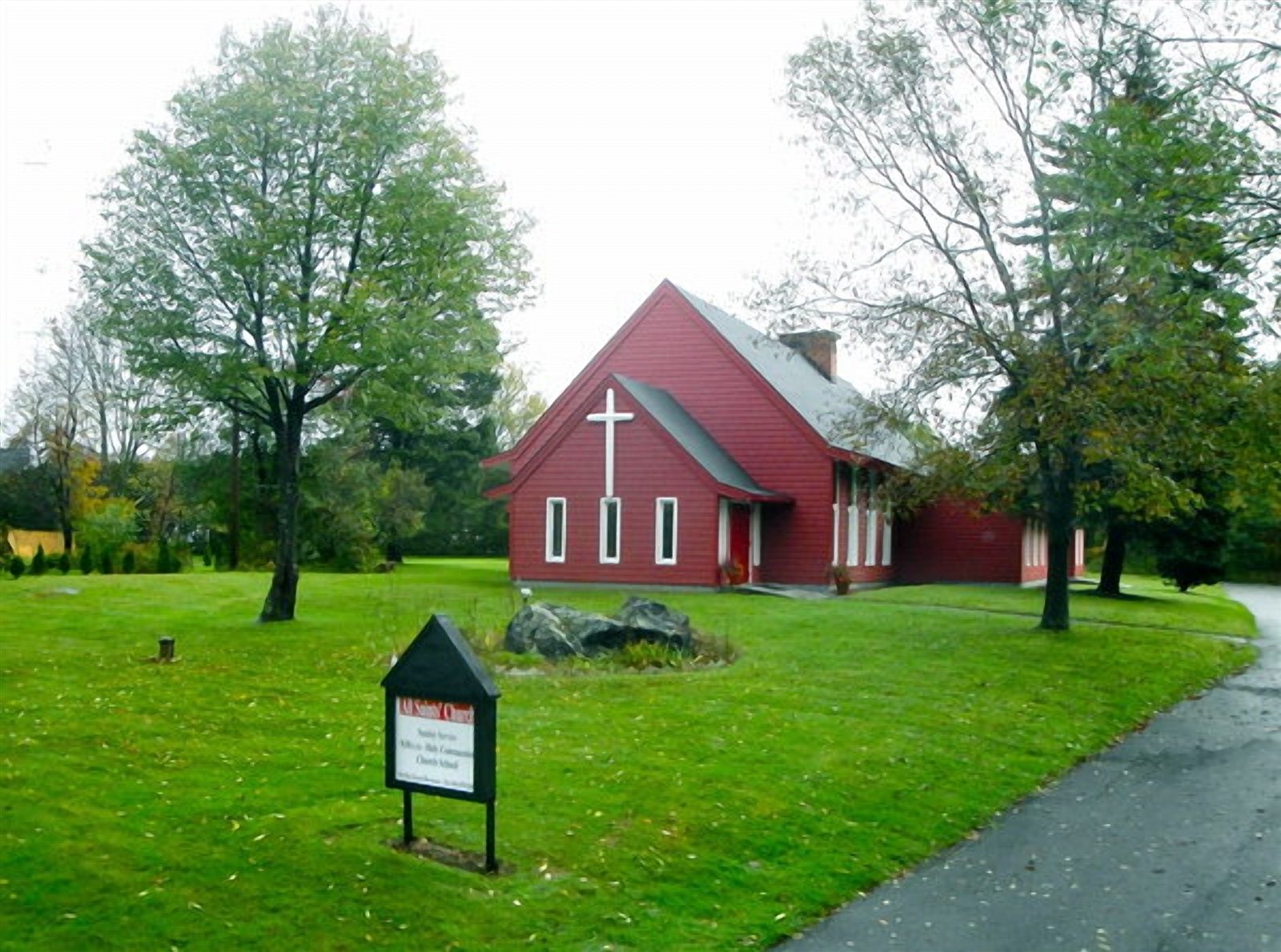All Saints' Episcopal Church, a red wooden chapel surrounded by trees and lawn